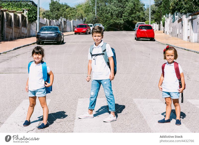 Schoolchildren with backpacks on crosswalk in city schoolchildren rucksack back to school commute friend childhood confident casual style road town boy girl