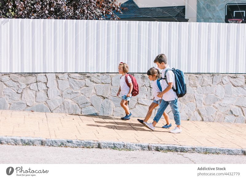 Schoolchildren talking while walking on sidewalk in town schoolchildren denim conversation friendship back to school childhood carefree stroll backpack