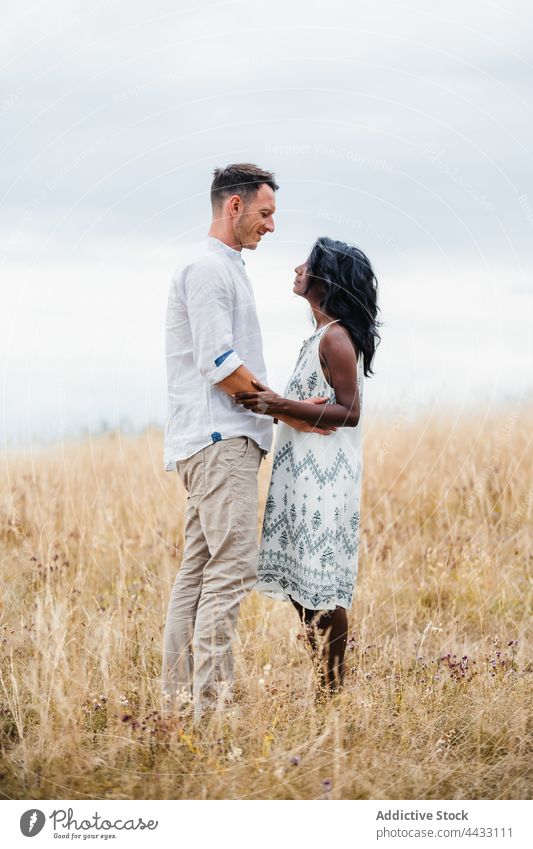 Multiethnic couple embracing on meadow in countryside embrace relationship love romantic spend time field nature sky indian multiethnic together grass boyfriend