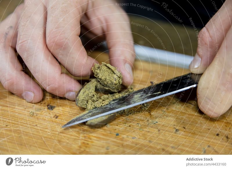 Crop man cutting dry marijuana piece on chopping board cannabis plant herb natural prepare workspace cbd ganja cannabinoid cannabinol thcp weed mary jane hemp