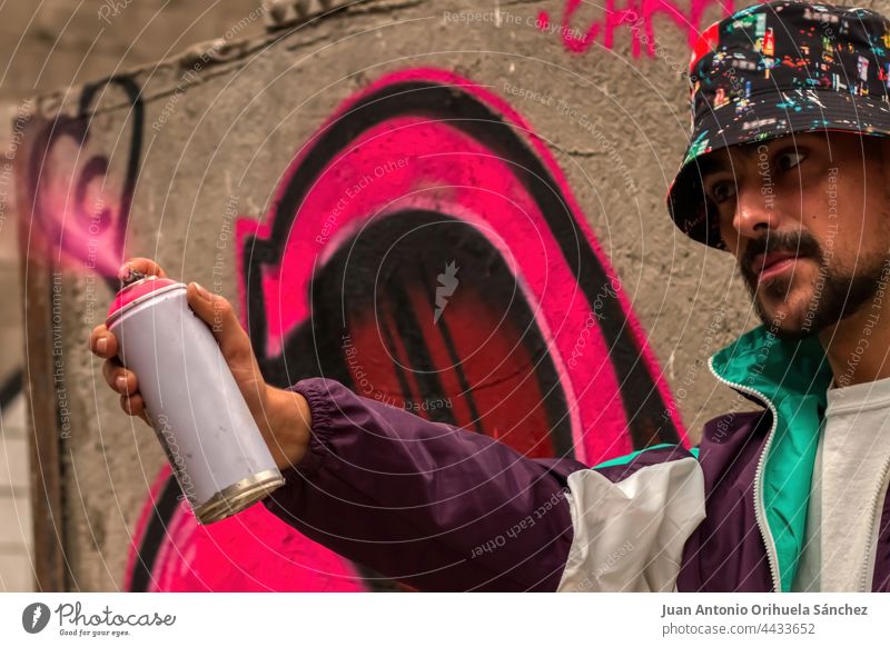 Graffiti artist with a spray in his hand where pink paint comes out guy man young lifestyle spray can graffiti painter creativity creative smiling modern adult