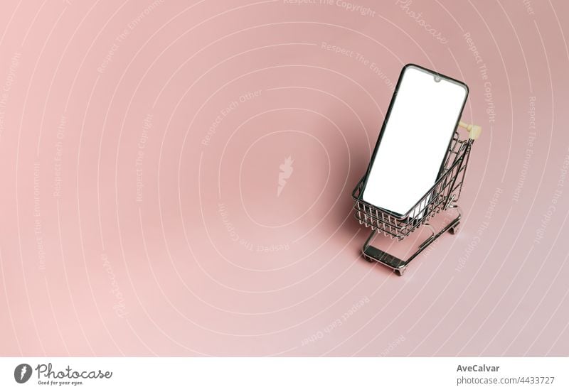Shopping cart with a blank mobile phone over a pastel pink background, e commerce, online buying, online commerce, background, technology, shopping day, black friday and network, copy space, mock up
