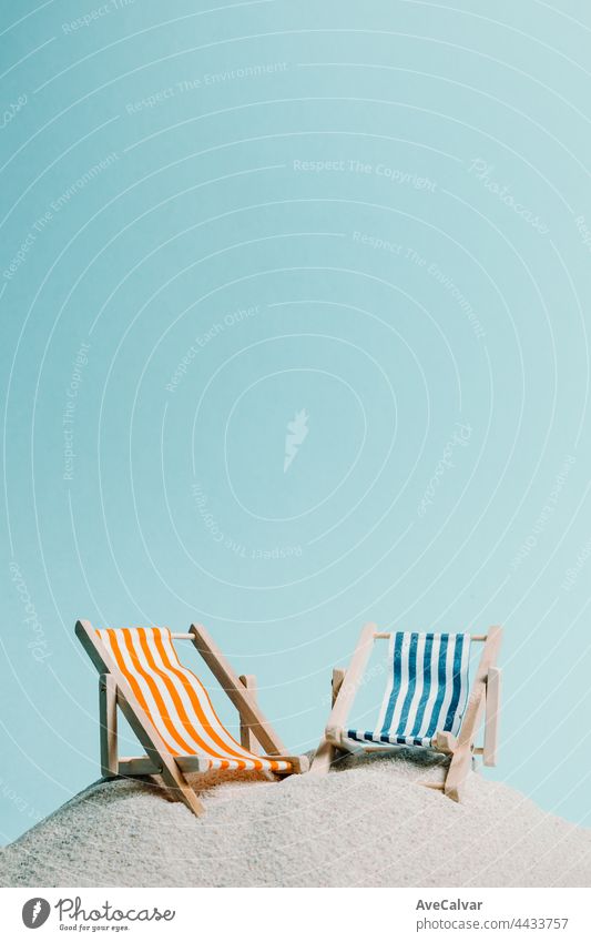 A pair of beach chair over the sand with a pastel blue background, copy space summer relax concept abstract sun journey art fun parasol composition creativity