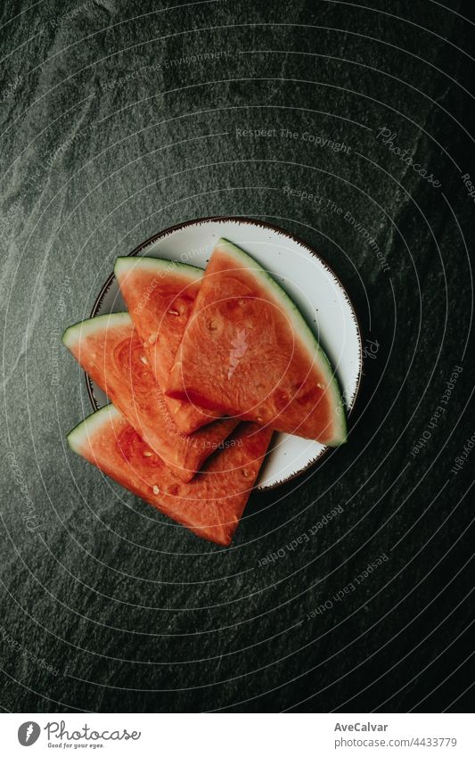 Aerial image of a dish filled with watermelon over a black marble table, fresh food, wellness, healthy food artist cherry fruits tasty healthy lifestyle juicy
