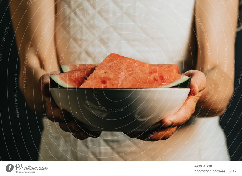 Old waitress offers and holds a watermelon in a dish, fruits, healthy life, good eating, mediterranean concepts, copy space, vertical image, summer eating, and refreshing fruits