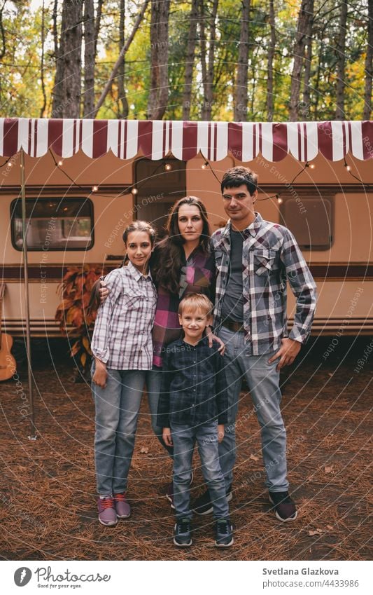 Happy family on a camping trip relaxing in the autumn forest. Camper trailer. Fall season outdoors trip fall nature father mother together fun happy people park