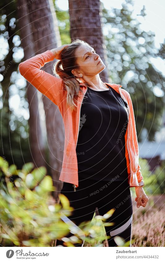 Sporty woman with ponytail stretching under trees Woman Stretching Distend pretty Athletic Heathland Sun Ponytail Orange Back-light Sports Jogging Walking
