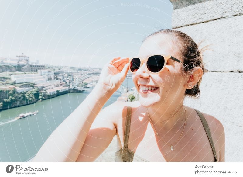 Young woman using sunglasses smiling a lot while touching them, sunglasses concept, summer and travel,copy space dress relaxation carefree fashionable joy hair
