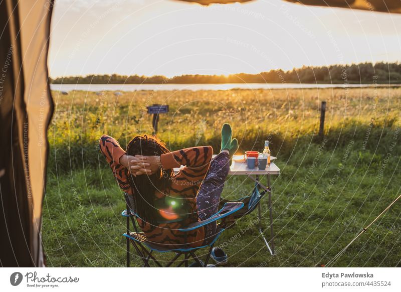 Woman relaxing in front of the tent during sunset campsite camping meadow grass field rural green countryside adventure hiking Wilderness wild vacation travel