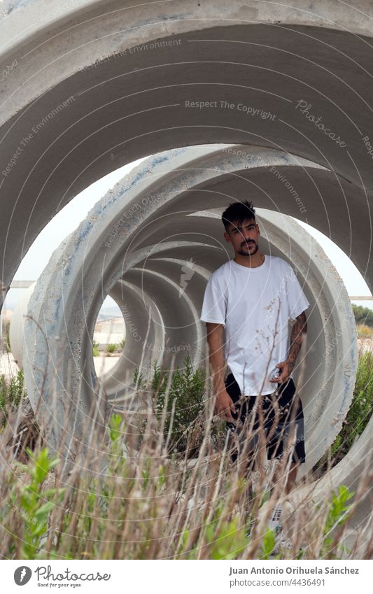 A handsome young man inside a large concrete pipe guy lifestyle creativity creative bizarre beard caucasian male macho spanish modern adult recreation