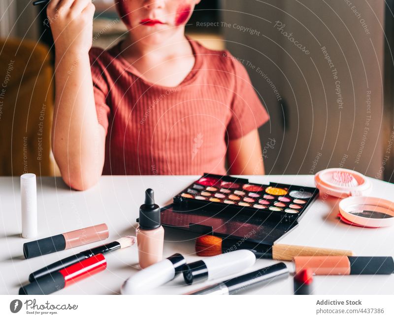 Boy applying makeup on face in house room boy applicator beauty cosmetic touch head decorative messy having fun portrait childhood palette product assorted