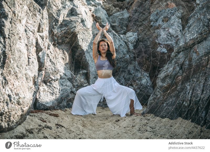 Asian woman doing Goddess pose in mountains goddess pose yoga arms raised wellness healthy lifestyle vitality energy portrait practice dry rough trousers