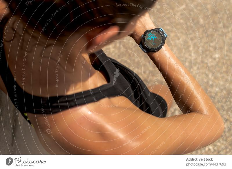 Crop sportswoman checking smartwatch during training fitness tracker smart watch runner pulse sweat bracelet female workout healthy athlete wristwatch wearable