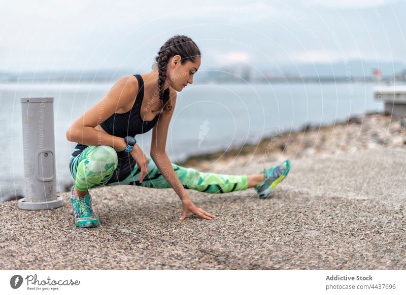 Flexible sportswoman stretching legs during workout lunge exercise training athlete embankment flexible warm up female side lunge practice fitness vitality