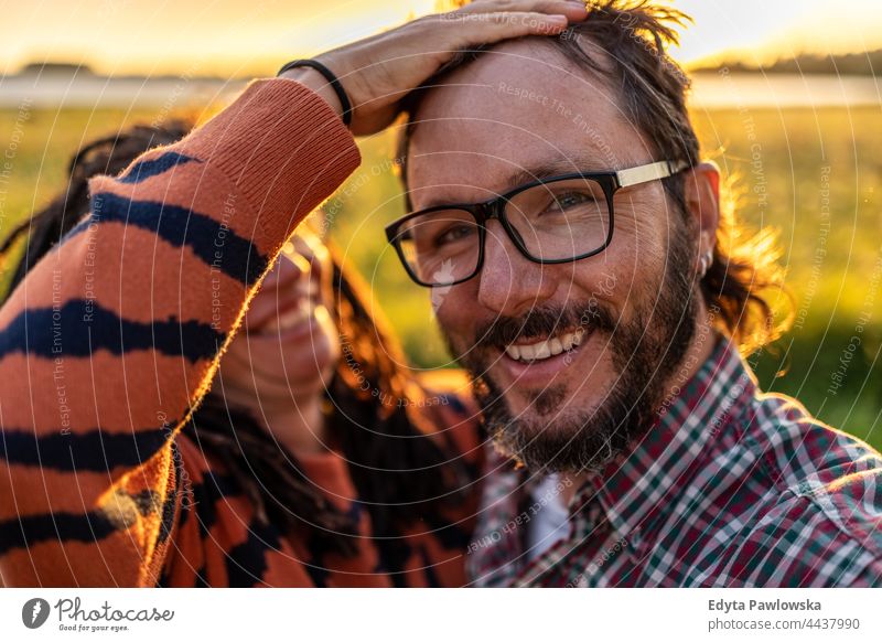 Portrait of a couple having fun outdoors at sunset real people authentic nature love together face woman person smiling adult hair glasses beard meadow field