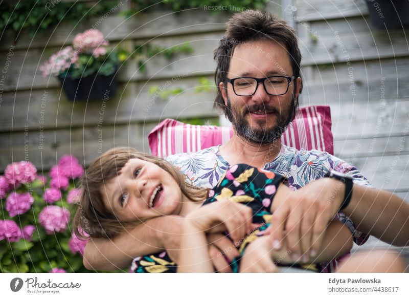 Dad playing with his daughter in the backyard real people authentic together father home parent love vacation active summertime day holiday tickle tickling