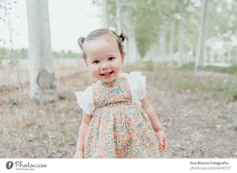 beautiful portrait of baby girl having fun outdoors in trees path. Children, fun and nature concept forest happy childhood smiling run caucasian Spain dress