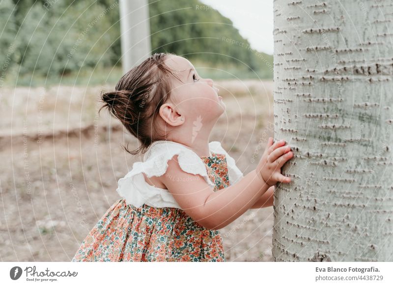 beautiful portrait of baby girl having fun outdoors in trees path. Children, fun and nature concept forest happy childhood smiling run caucasian Spain dress
