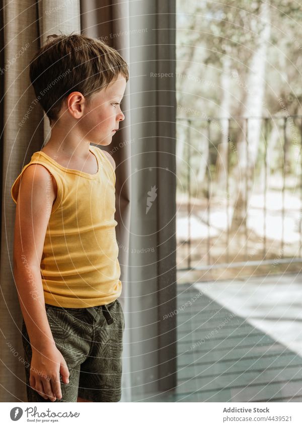 Boy standing near window in house child thoughtful boy pensive kid little tranquil calm childhood home peaceful adorable harmony contemplate serene dreamy cute