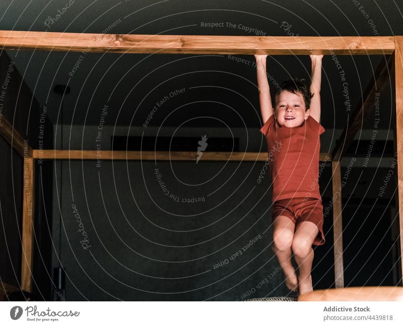 Cheerful boy hanging on canopy bed child having fun bedroom cheerful entertain cute kid childhood little positive carefree smile home enjoy playful happy