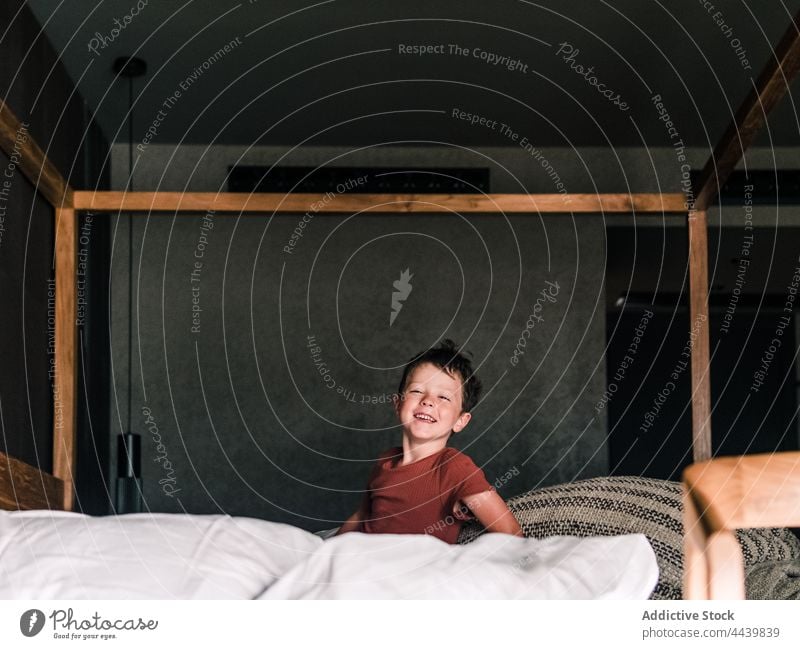 Cheerful boy on canopy bed child having fun bedroom hang cheerful entertain cute kid childhood little positive carefree smile home enjoy playful happy weekend