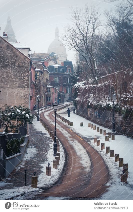 Winding narrow snowy road through old buildings on hill Montmartre district historic mist culture architecture heritage winter haze history travel street curve