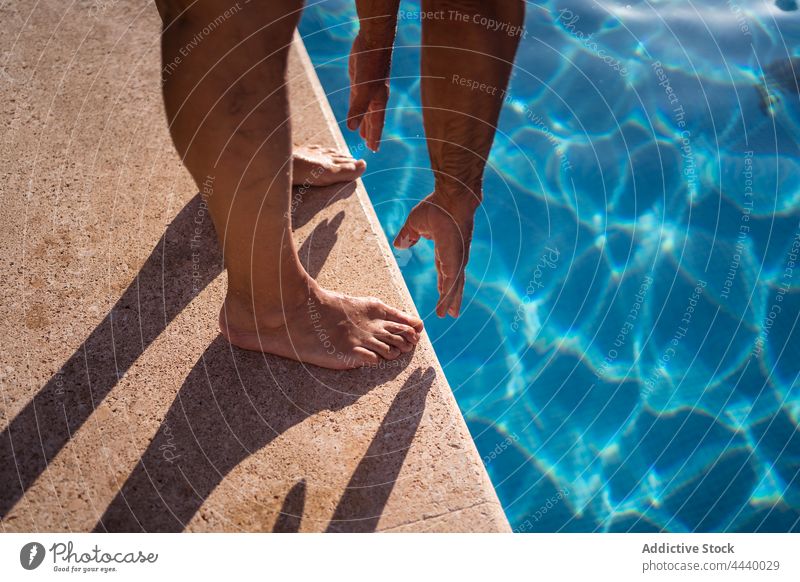 Person bending forward on edge of pool person poolside clean water flexible barefoot stretch vacation bend forward resort wellness tourist warm up sunlight wet