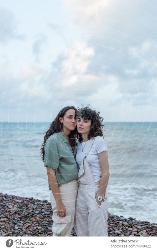 Homosexual couple of women embracing on sea shore embrace lesbian relationship love soulmate romantic seashore cloudy portrait sky girlfriend ocean together