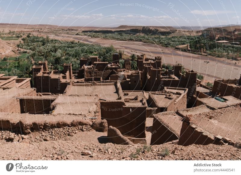 Ksar against river and green trees under blue sky ksar architecture exterior nature sightseeing historic medieval village tropical fortress facade environment