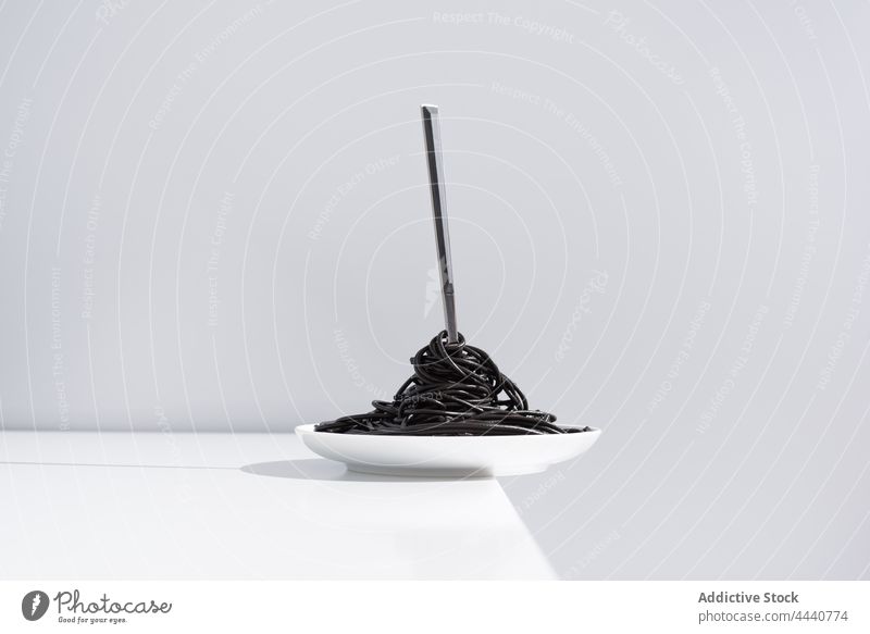 Fork in bowl of delicious Italian pasta fork black portion culinary meal food serve cuisine table nutrition tradition cuttlefish ink squid ink tasty lunch dish