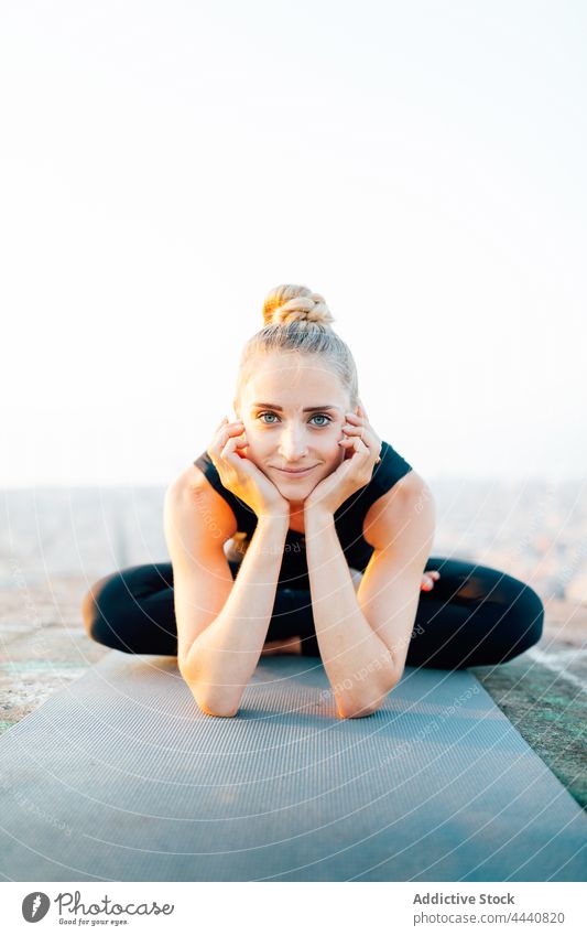 Smiling woman doing Half Lotus and leaning on hands half lotus positive sunset recovery asana yoga wellness practice sporty female ardha padmasana lean on hand