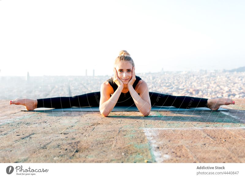 Flexible woman in Wide Splits pose on sports mat wide splits spirit yoga sundown posture rooftop stretch body care flexible female asana upavishta konasana