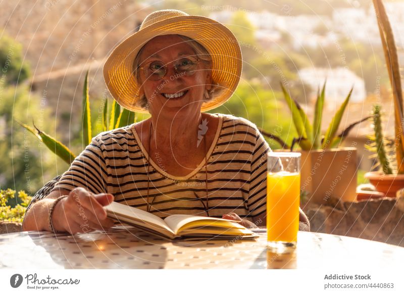 Old woman reading book in cafe senior hobby literature pastime interest leisure female elderly old novel aged gray hair beverage table retire bookworm wrinkle