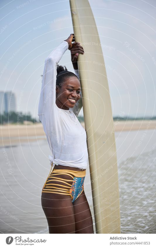 Black surfer with longboard contemplating sea from beach sport surfing contemplate ocean nature blue sky woman sportswoman black ethnic african american admire