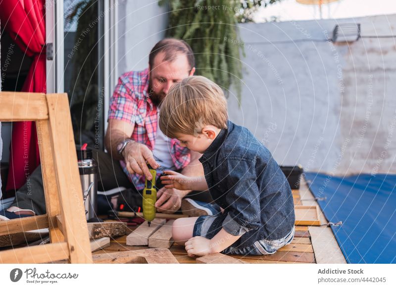 Father with son measuring wooden pieces with tape father measure woodwork handmade attentive precise childhood man hipster tool dad accuracy handwork diy