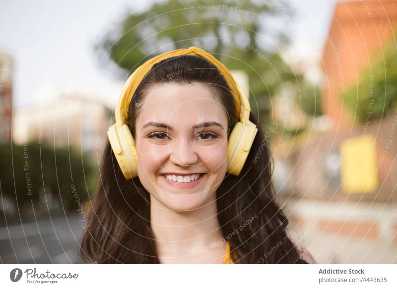 Cheerful woman in headphones walking on the street music listen wireless positive hobby enjoy carefree song female gadget delight audio millennial pleasure