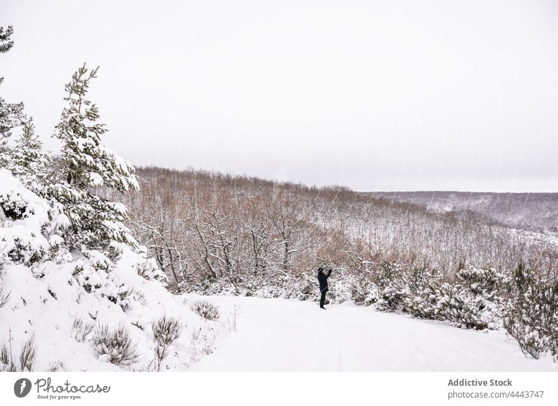 Traveler standing on snowy slope on hill in wintertime person nature countryside traveler hiker highland mobile phone cold tree landscape photographer picture