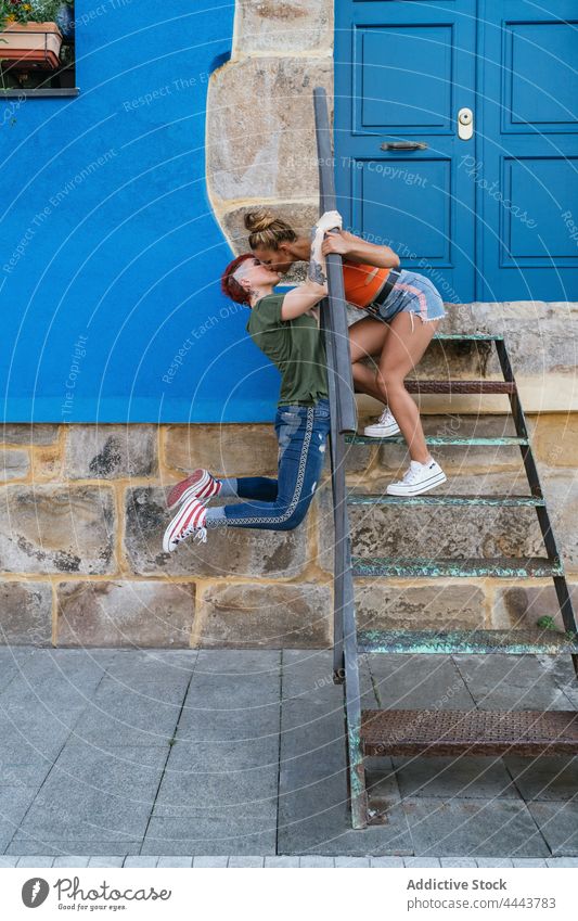 Lesbian couple kissing against urban house with stairs amour relationship romantic lgbt cool building women pleasure love hang girlfriend lesbian legs raised