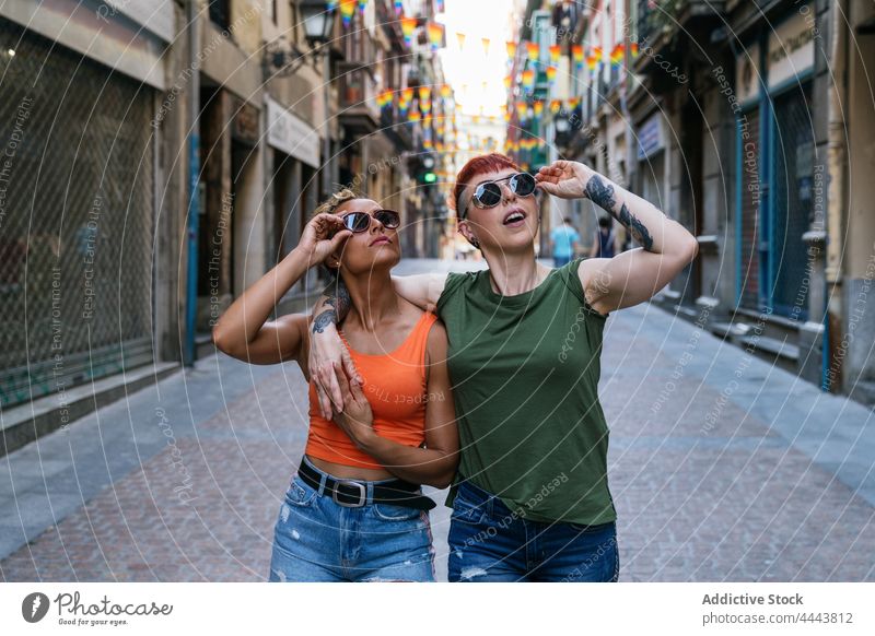 Lesbian girlfriends in modern sunglasses embracing on urban pavement embrace lesbian tattoo fashion cool trendy surprised town women homosexual wear lgbt couple