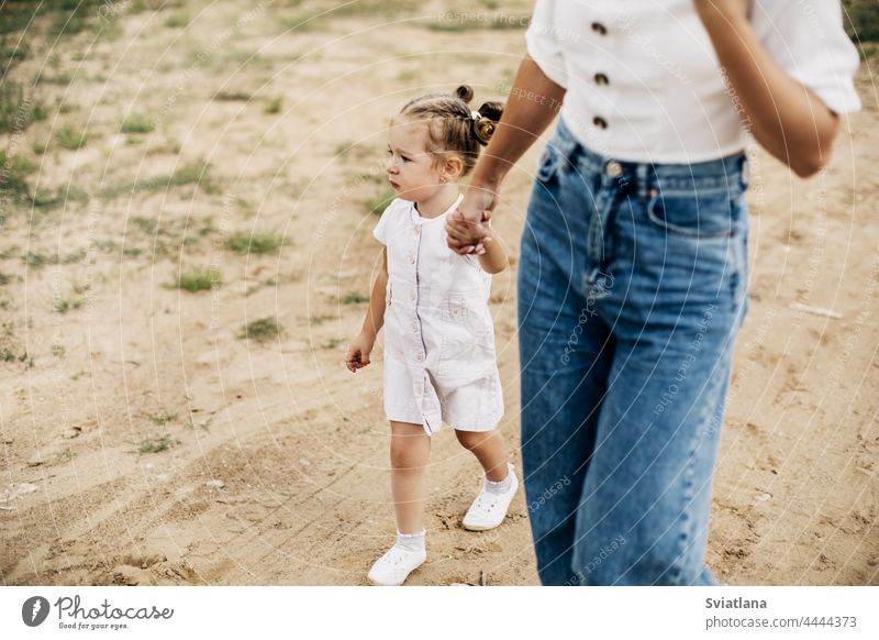 Mom and her little daughter are walking, holding hands, spending time together mother woman girl kid love nature people mom day child family childhood happiness