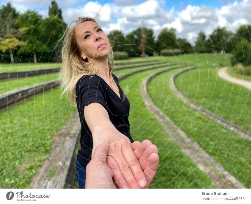 Portrait of happy female person smiling and looking at the camera outdoors in the nature. A blond woman holding hand of a man. adult adventure attractive