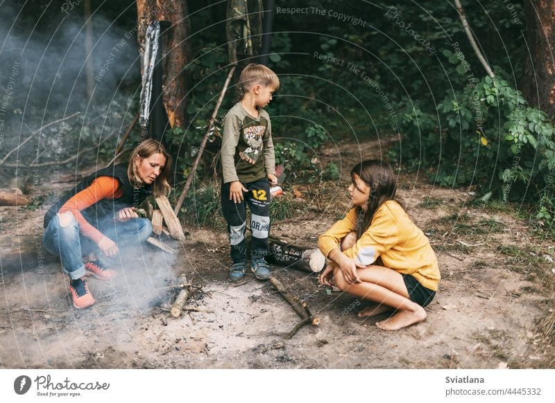A happy family makes a fire during a trip in the forest. Spending time together, family time mom daughter son campfire relationship weekend
