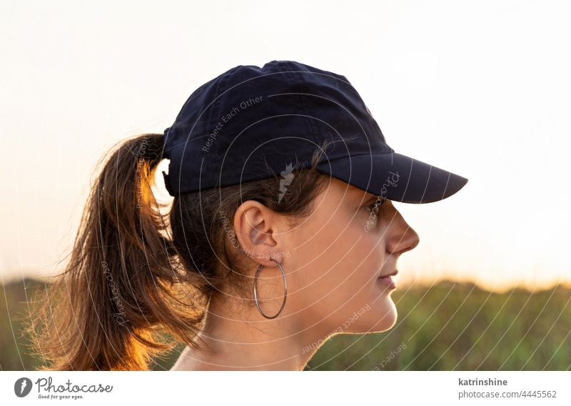 Teen girl in dark blue baseball cap at sunset outdoor teenager adolescent Caucasian mockup visor head wearing teen girl childhood female happiness pony tail