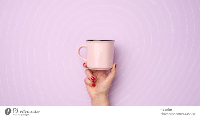 female hand holding a pink ceramic mug on a purple background, break time and drink coffee, banner up adult arm beverage blank breakfast cappuccino clean