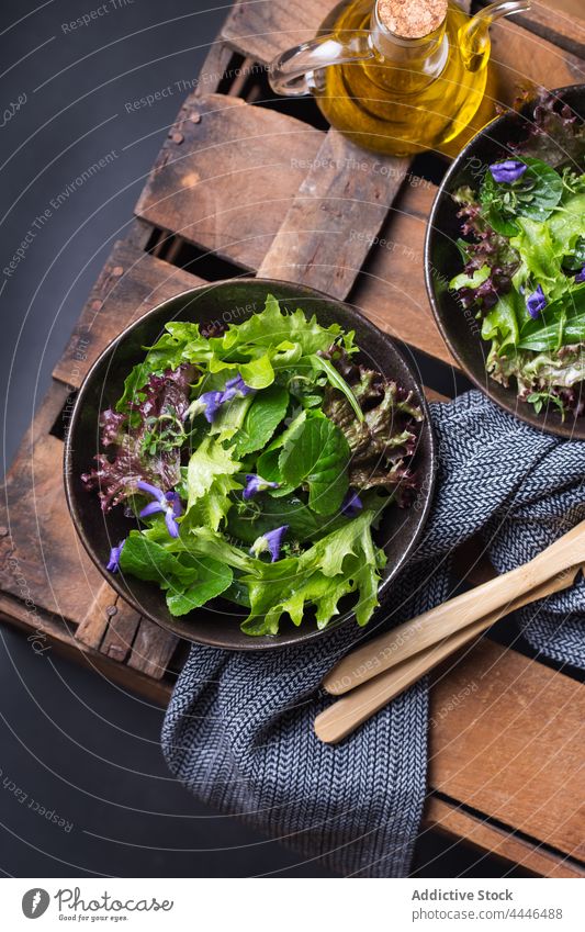 Delicious lettuce and wildflower salad in bowls on dark background healthy food vegetarian vegetable natural fresh oil delicious vitamin nutrient leaf portion