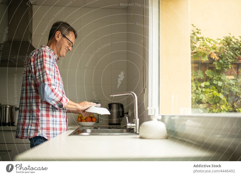 Man washing dishes in kitchen at home man household cleanse window single stand leisure soap husband dishware kitchenware chore plate side view routine human