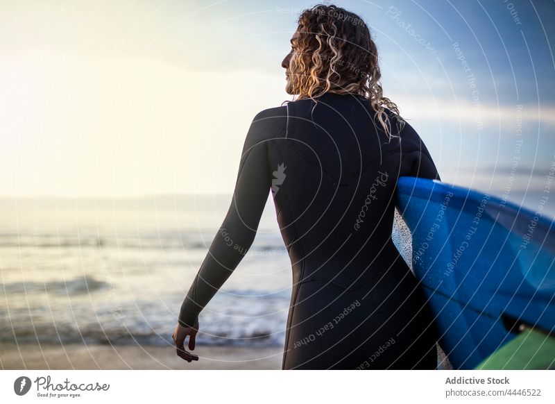 Woman standing in the shore with surfboard looking at the sea during sunset woman sunrise wetsuit sportswoman fun contemplate waves sunshine female surfer water