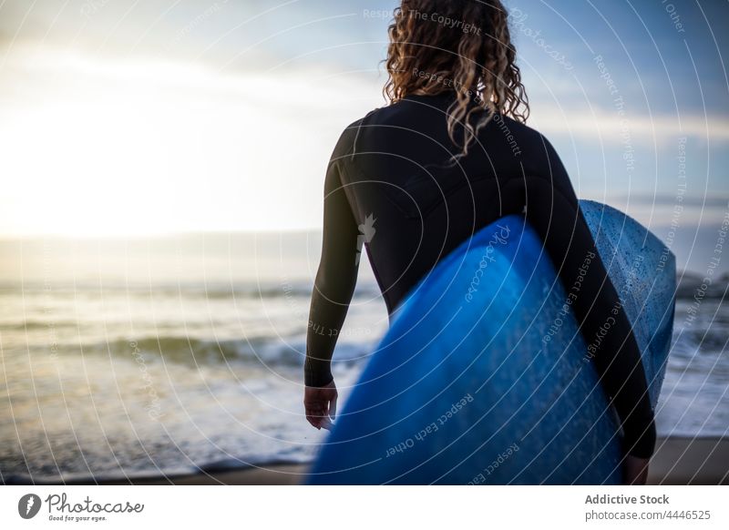 Woman standing in the shore with surfboard looking at the sea during sunset woman sunrise wetsuit sportswoman fun contemplate waves sunshine female surfer water