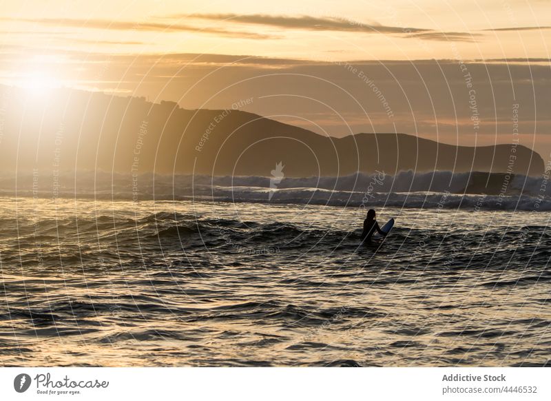 Woman surfing in the sea during sunset woman sunrise wetsuit surfboard sportswoman fun silhouette waves sunshine female vacation surfer water beautiful ocean