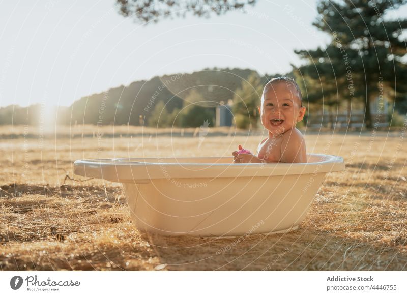 Cheerful baby having fun in small bath play cheerful carefree toy drop countryside innocent child toddler glad drip babyhood enjoy laugh cute kid childhood